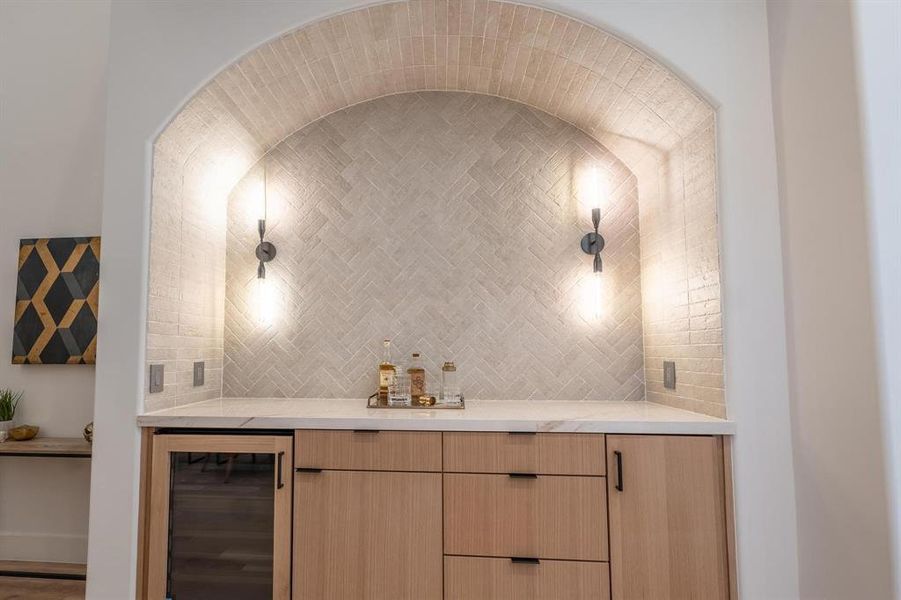 Bar featuring wine cooler, tasteful backsplash, and light brown cabinetry