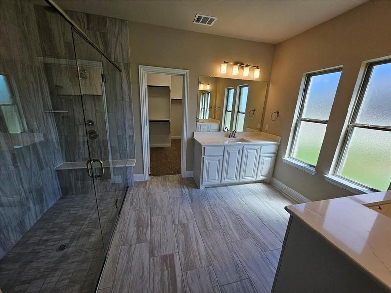 Spa-like master bathroom featuring huge walk-in shower with 2 benches, 4 shower heads, and dropped tile floor.