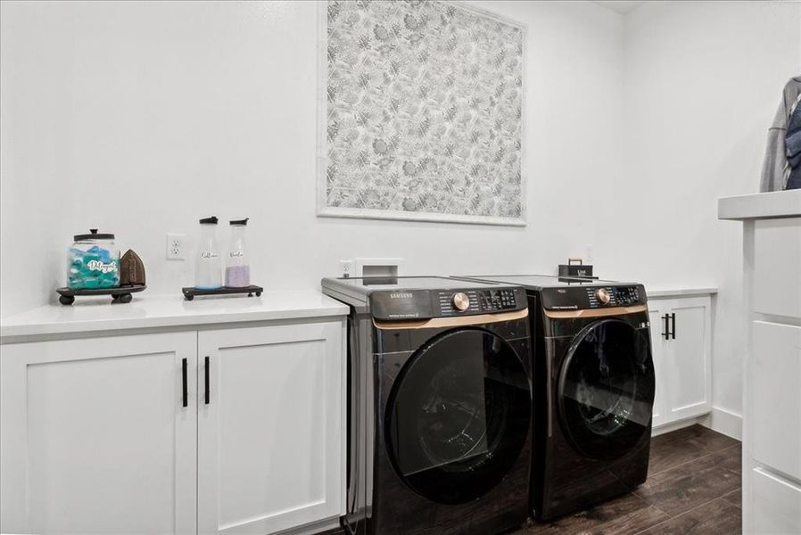 Laundry area featuring cabinets, dark hardwood / wood-style flooring, and washer and dryer