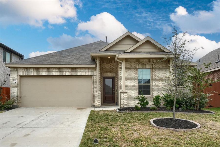 View of front facade featuring a front yard and a garage