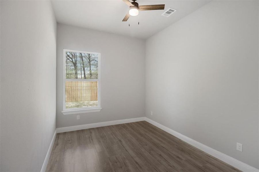 Unfurnished room with hardwood / wood-style flooring, a wealth of natural light, and ceiling fan