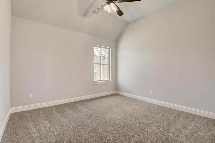 Carpeted empty room with lofted ceiling and ceiling fan