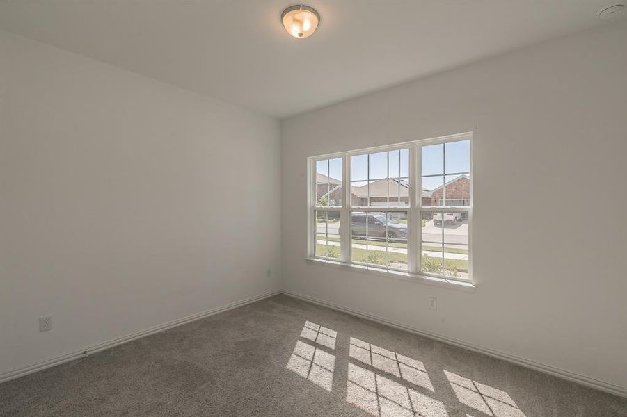 Spare room featuring dark carpet and plenty of natural light