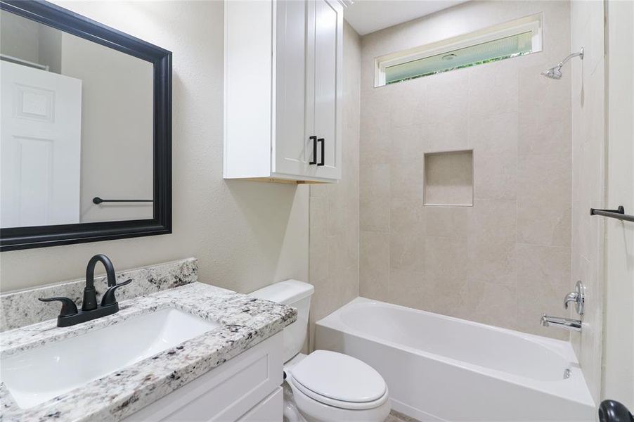 Secondary bath with over the toilet cabinets, behind the door shelving, and tub/shower combo