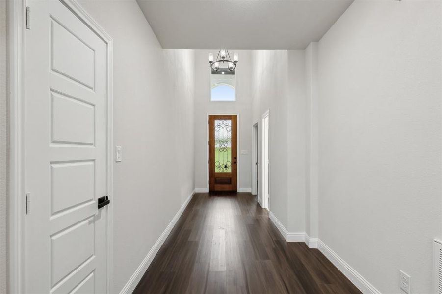 Doorway to outside with dark hardwood / wood-style floors and a notable chandelier