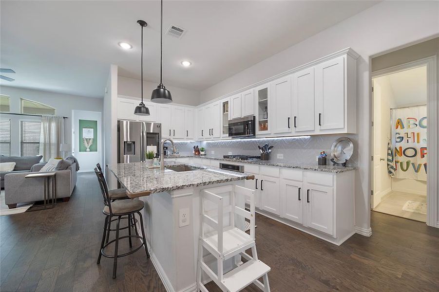 Kitchen featuring appliances with stainless steel finishes, white cabinets, sink, and dark wood-type flooring