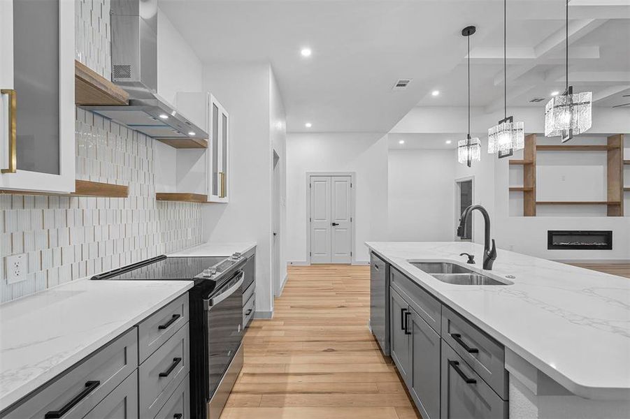 Kitchen featuring light hardwood / wood-style flooring, appliances with stainless steel finishes, sink, decorative backsplash, and wall chimney range hood