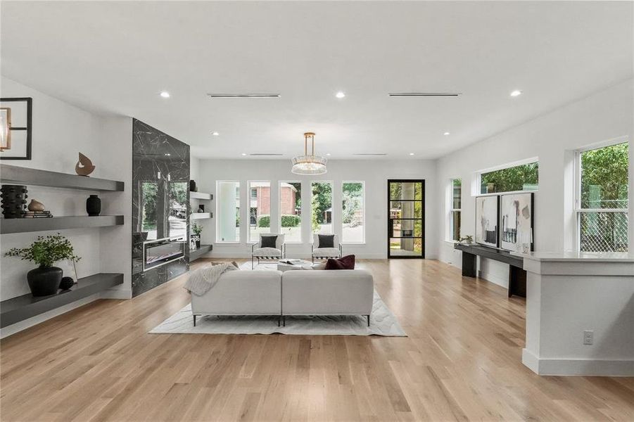 Living room with a high end fireplace and light wood-type flooring