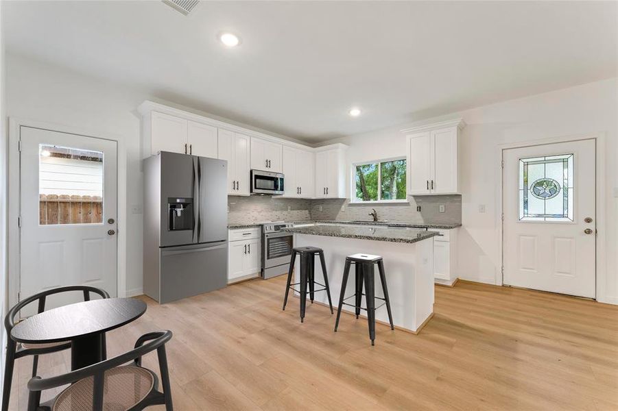 The open-concept design seamlessly blends the breakfast nook with the sleek and functional kitchen, creating a space perfect for gatherings. (Virtual Staging May Be Present)