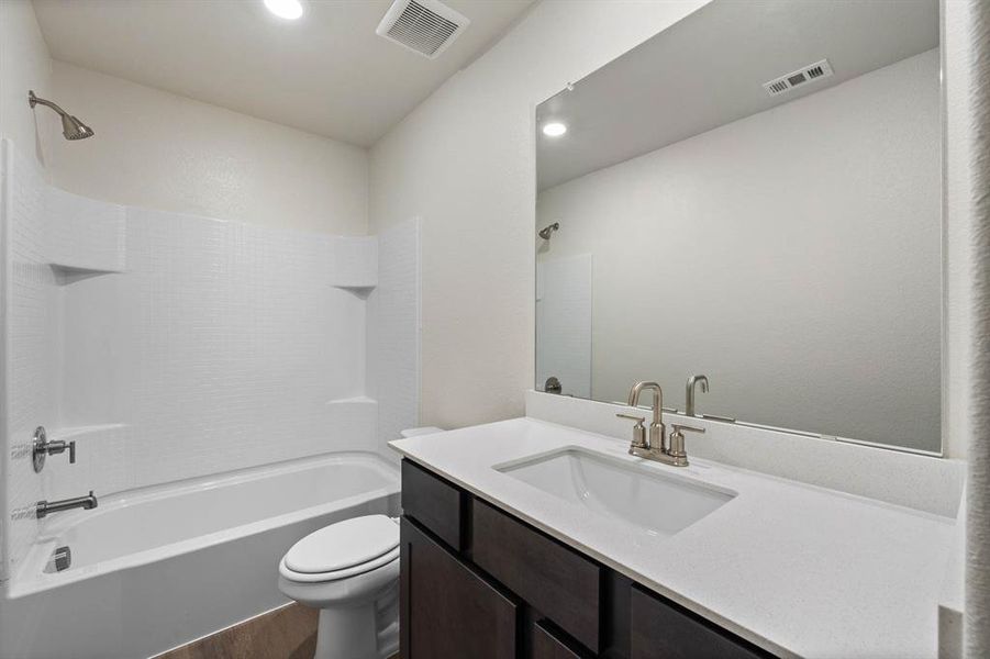 Full bathroom featuring vanity, wood-style floors, washtub / shower combination, and toilet