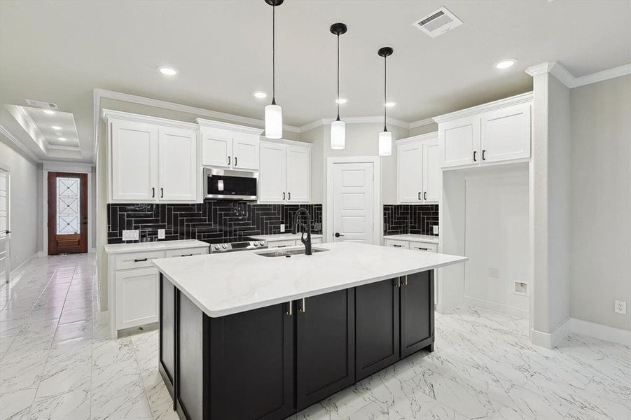Kitchen featuring sink, a kitchen island with sink, and white cabinets