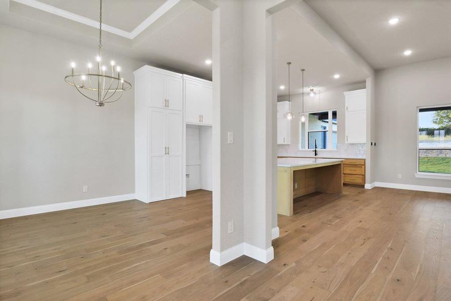 Kitchen with tasteful backsplash, pendant lighting, light hardwood / wood-style flooring, a spacious island, and white cabinetry