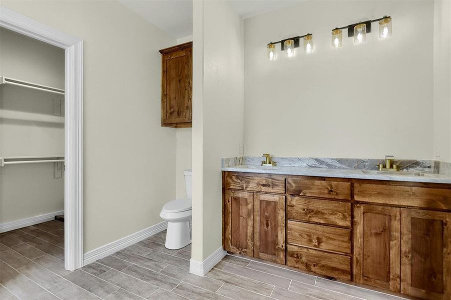 Bathroom featuring toilet and dual bowl vanity. Mirrors now installed