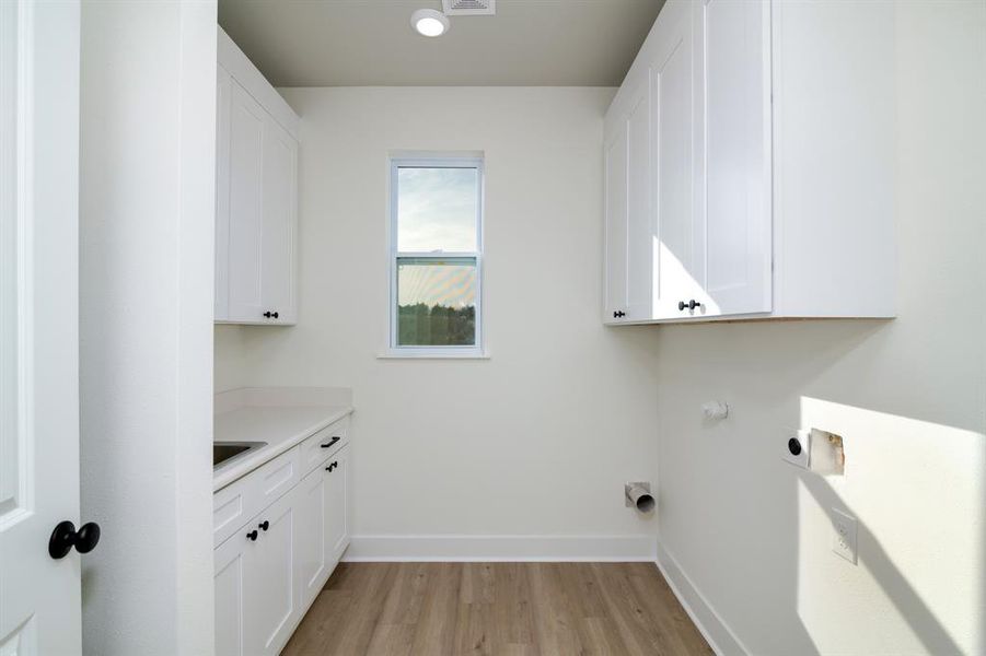 Laundry room featuring cabinets, light hardwood / wood-style floors, and hookup for an electric dryer