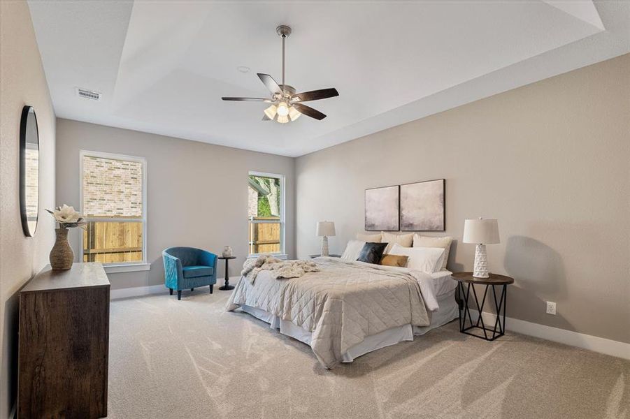 Bedroom featuring a tray ceiling, ceiling fan, and light carpet