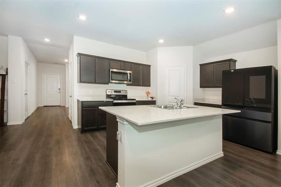 Kitchen featuring dark brown cabinets, dark hardwood / wood-style floors, stainless steel appliances, sink, and a center island with sink