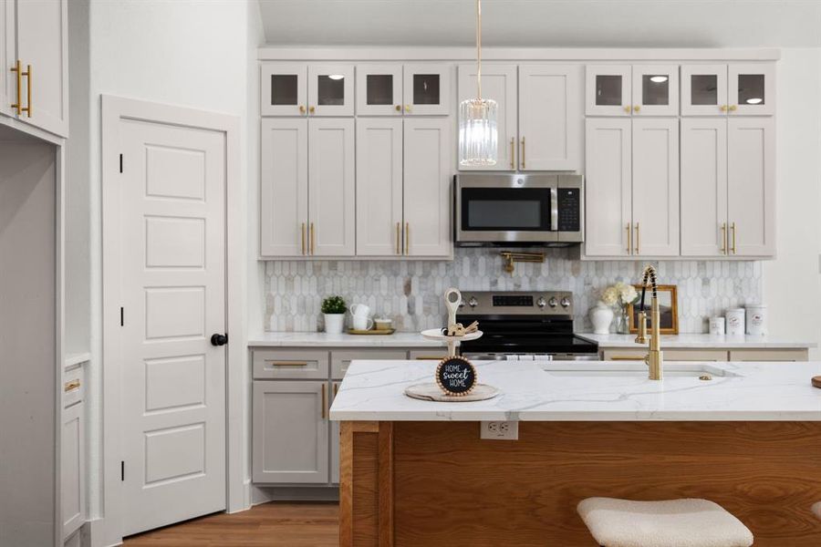 Kitchen with sink, appliances with stainless steel finishes, white cabinetry, and a breakfast bar