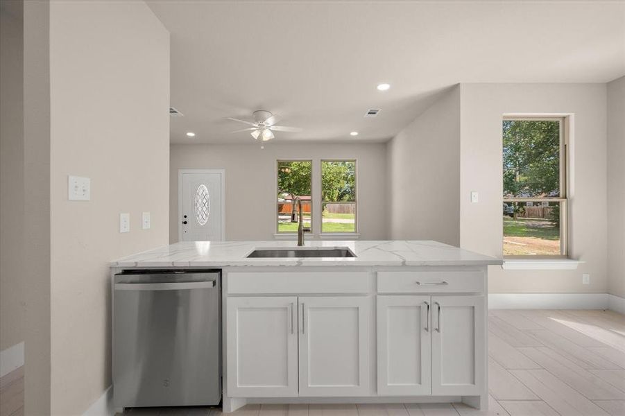 Kitchen with sink, stainless steel dishwasher, white cabinetry, and ceiling fan