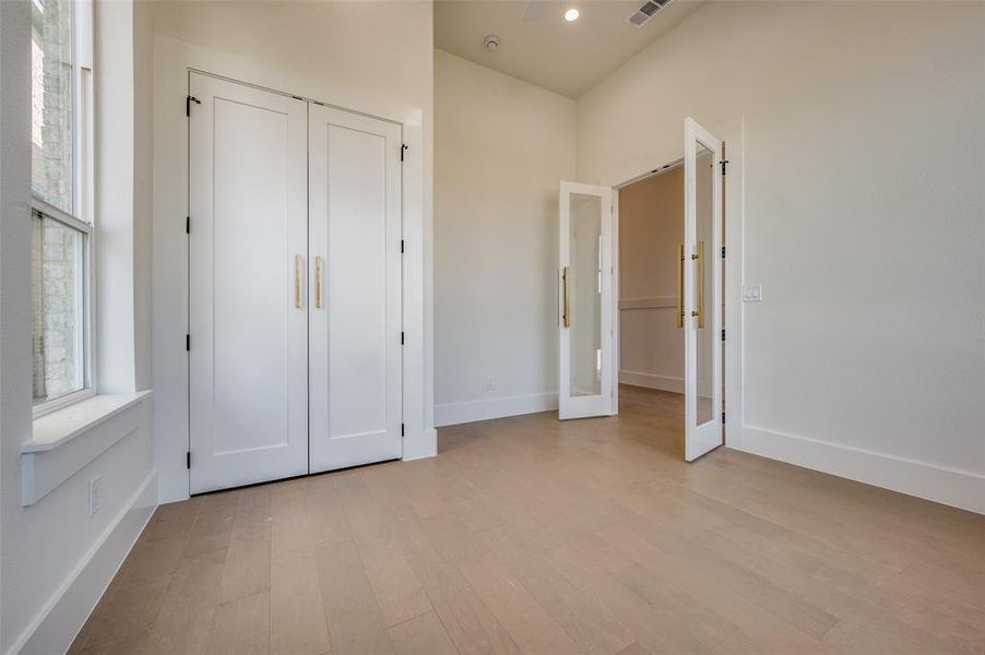 Unfurnished bedroom featuring light hardwood / wood-style floors, a closet, and french doors