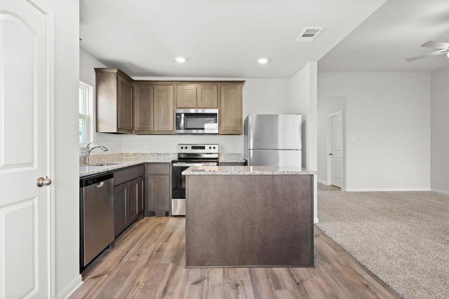 Kitchen with ceiling fan, sink, stainless steel appliances, and light hardwood / wood-style floors