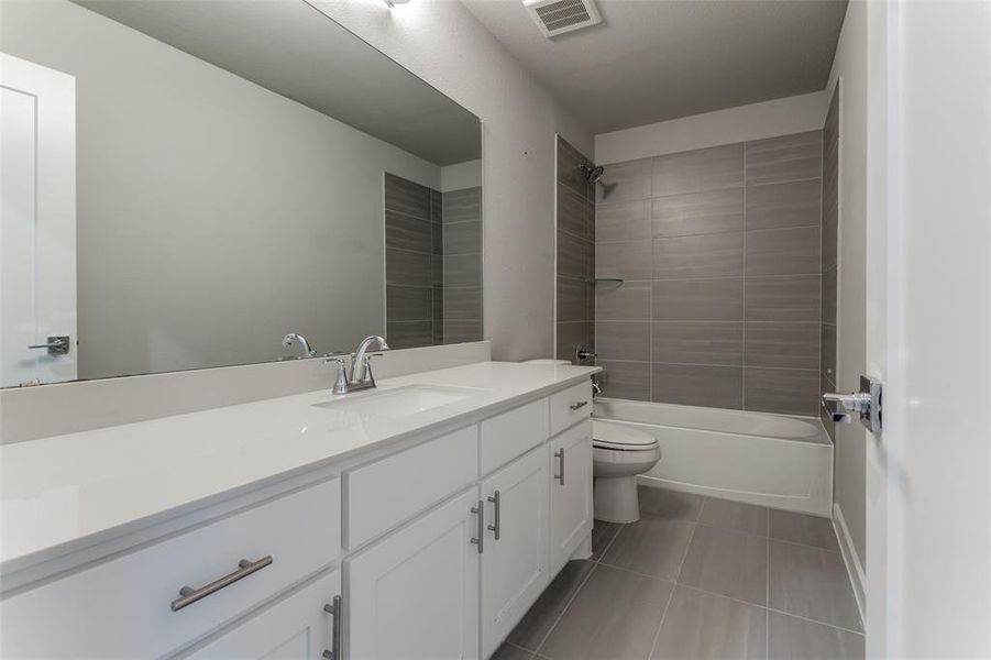 Full bathroom featuring tiled shower / bath combo, vanity, tile patterned floors, and toilet