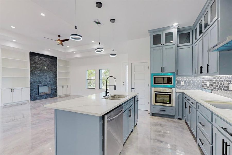 Kitchen featuring appliances with stainless steel finishes, sink, a fireplace, ceiling fan, and a raised ceiling