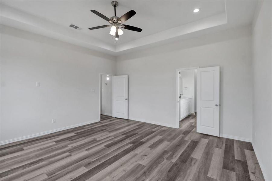 Empty room with ceiling fan, a raised ceiling, hardwood / wood-style floors, and a towering ceiling