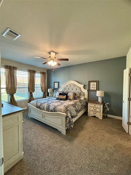 Carpeted bedroom featuring a textured ceiling and ceiling fan