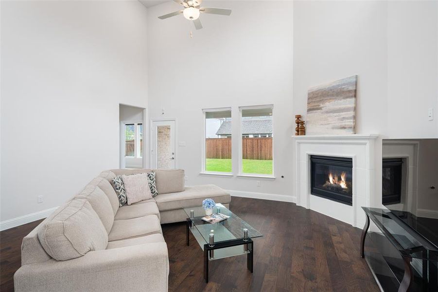 Living room featuring ceiling fan, dark hardwood / wood-style flooring, and a towering ceiling