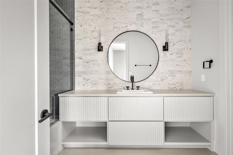 This ensuite bath exudes elegance with its tiled walls that extend to the ceiling, an oversized vanity offering ample storage, and a luxurious shower/tub combo, perfect for a spa-like retreat.