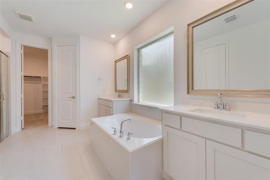 Bathroom featuring tile patterned flooring, a bath, and double vanity