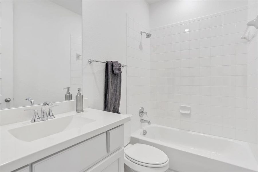 Full bathroom with tiled shower / bath combo, toilet, and vanity