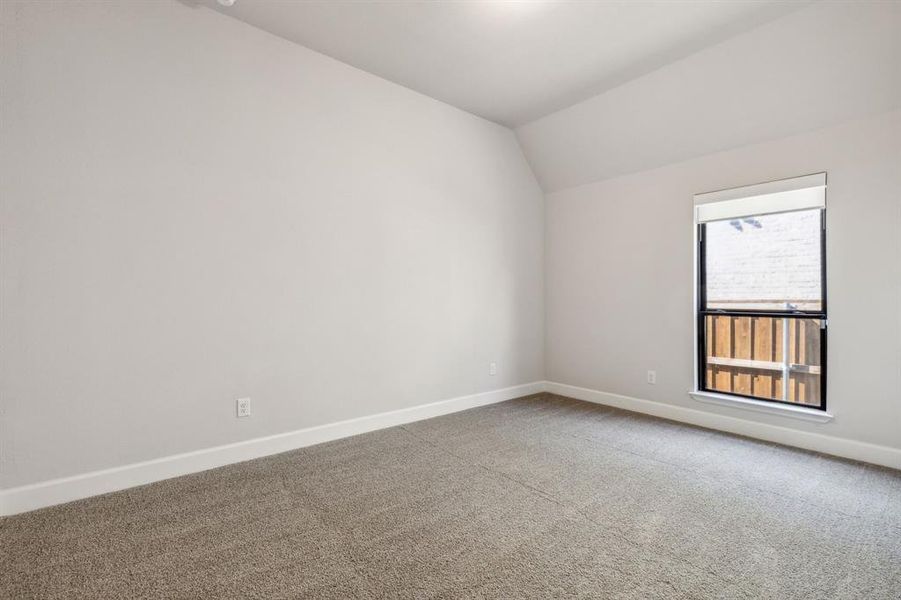 Empty room with lofted ceiling and carpet floors