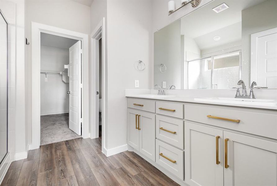 Bathroom with dual vanity, wood-type flooring, and an enclosed shower