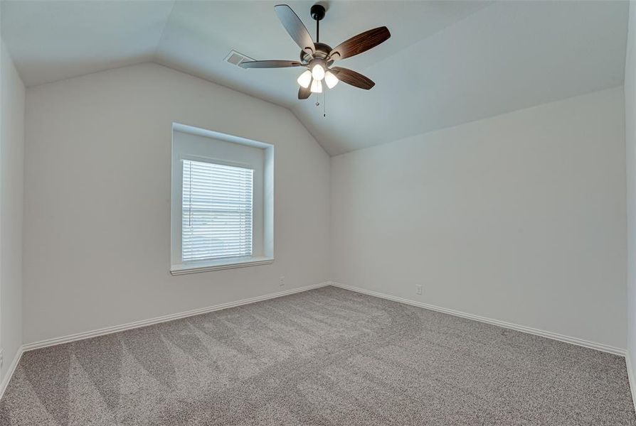 Empty room with carpet flooring, ceiling fan, and vaulted ceiling