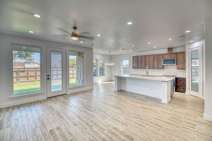 Kitchen featuring a healthy amount of sunlight, stainless steel appliances, a center island with sink, and a kitchen bar