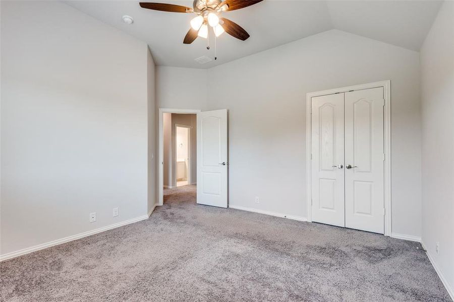 Unfurnished bedroom with lofted ceiling, light carpet, ceiling fan, and a closet