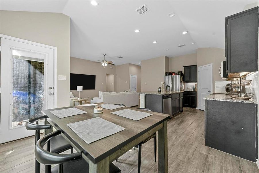 Dining room with light hardwood / wood-style floors, ceiling fan, and vaulted ceiling