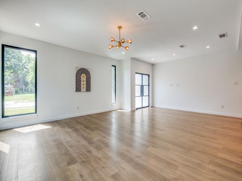 Unfurnished living room featuring light hardwood / wood-style floors and a notable chandelier