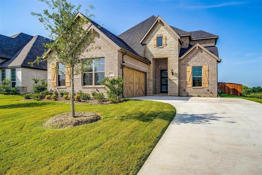 French country home with a garage and a front lawn