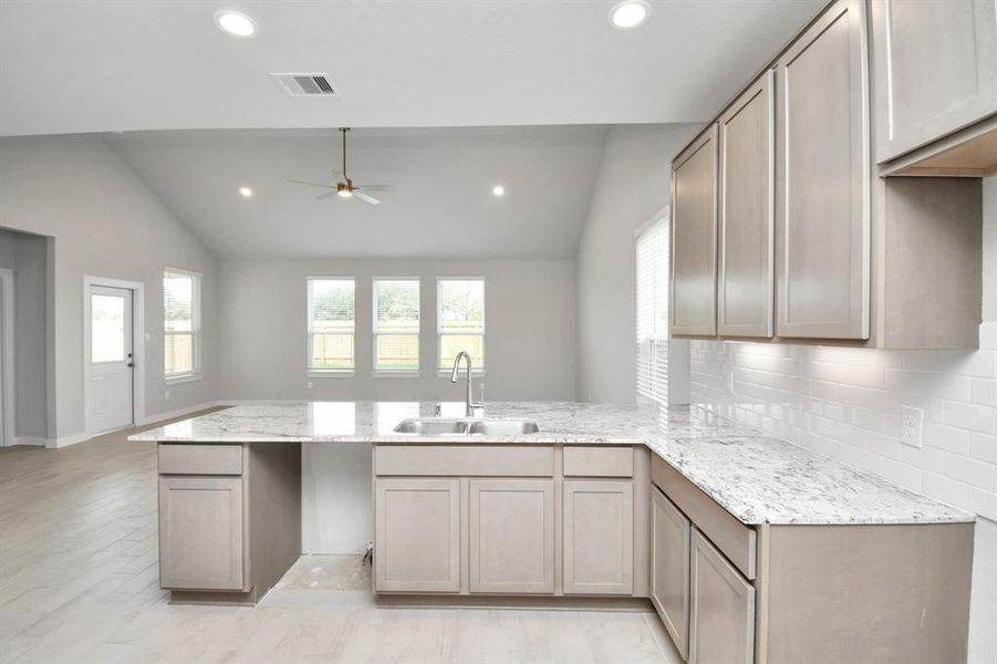 The kitchen is a culinary haven, featuring granite countertops, a tile backsplash, stainless steel appliances, 42” upper cabinets, and undercabinet lighting. Sample photo of completed home with similar floor plan. Actual colors and selections may vary.