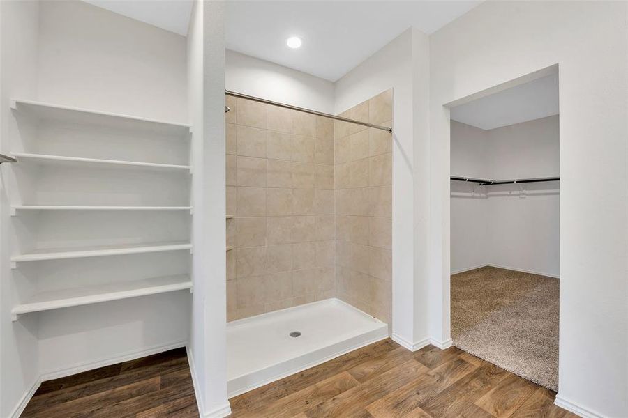 The primary bath as a large shower and additional shelving for linens and bath supplies. The doorway to the right leads you to a large closet.