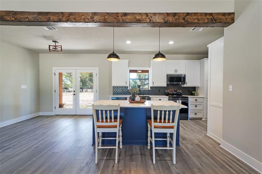 Kitchen with hanging light fixtures, a breakfast bar, electric range, a center island, and hardwood / wood-style flooring