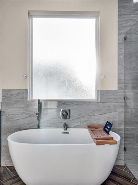 Bathroom with hardwood / wood-style flooring, tile walls, and separate shower and tub