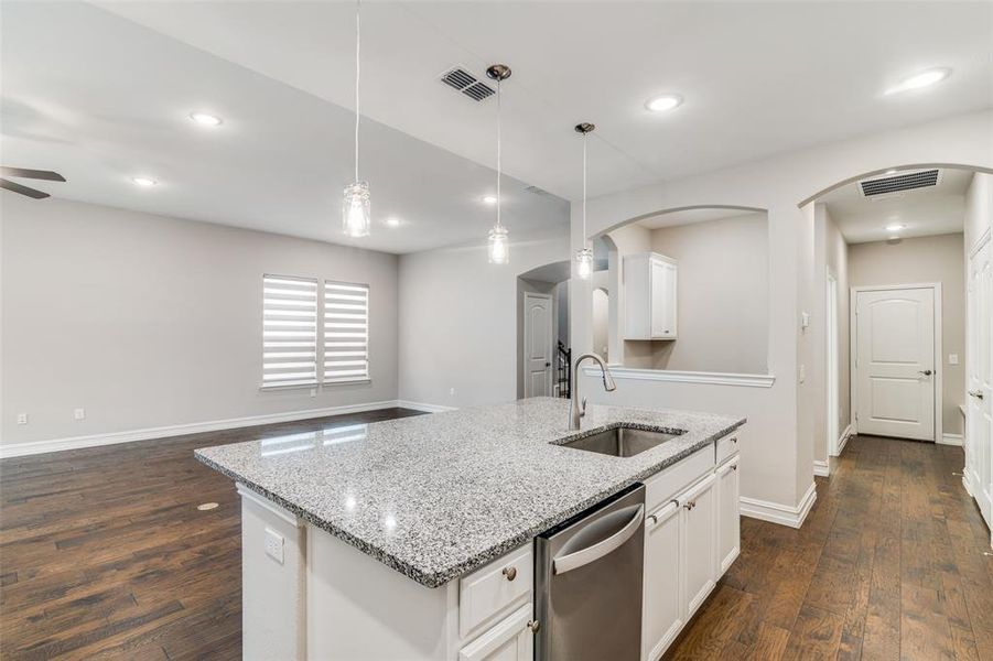 Kitchen with dishwasher, sink, dark hardwood / wood-style floors, ceiling fan, and a center island with sink