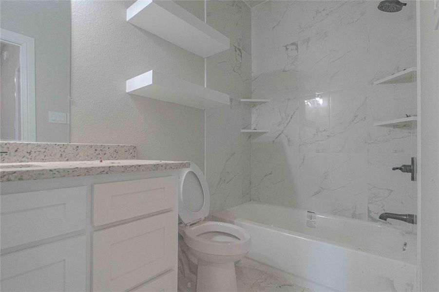 Full bathroom with tile flooring, oversized vanity, toilet, and tiled shower / bath combo