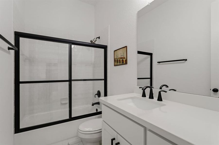 This ensuite off the guest bedroom is sleekly designed with quartz countertops and modern black glass doors to the shower/tub combo.