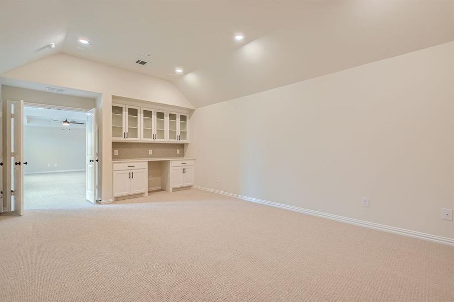 Spare room featuring vaulted ceiling, ceiling fan, and light colored carpet