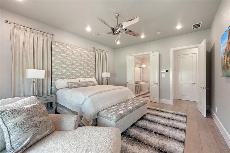 Bedroom with ceiling fan, light hardwood / wood-style floors, and ensuite bath