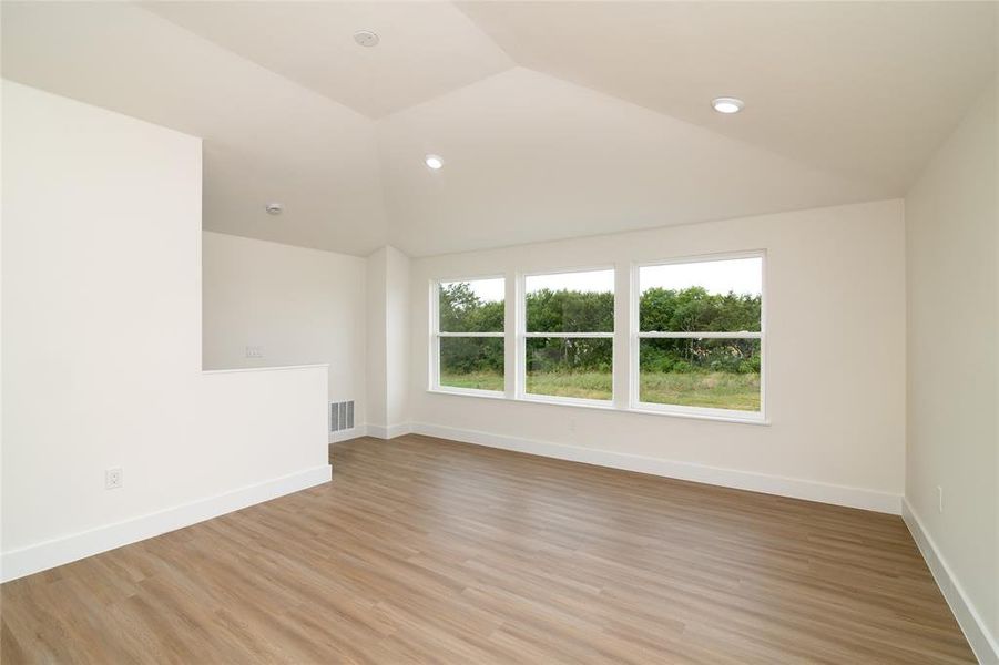 Upstairs Half story featuring light wood-type flooring and vaulted ceiling